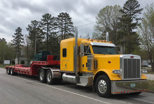 Yellow flatbed truck transporting freight representing hauling services